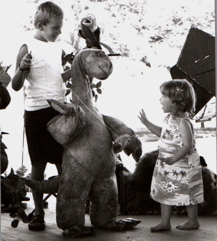 Boy with one of Penelope's dinosaur puppets entertaining a child.