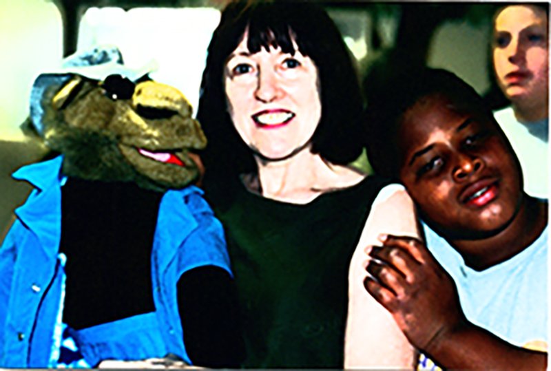 A camel puppet named Clyde with a student and a teacher.